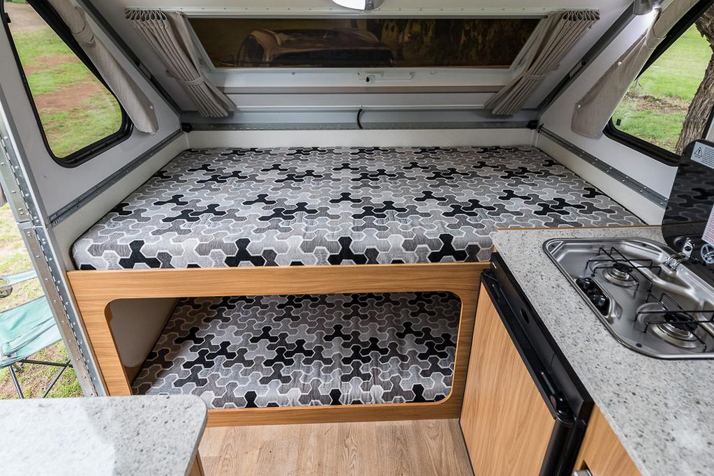 Factory bunk layout in an Avan Cruiseliner with patterned mattresses over the under-bunk, next to the kitchenette