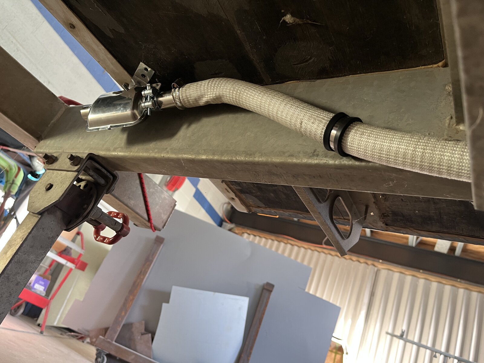 Stainless exhaust silencer and heat-resistant hose bracketed under chassis rail