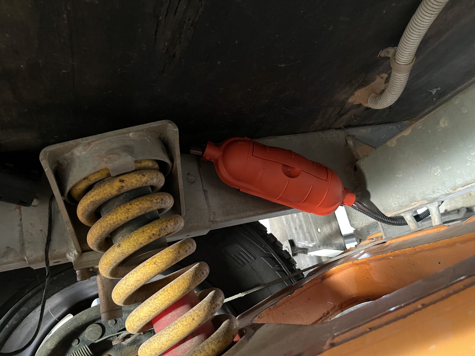 Red fuel metering pump mounted at correct angle on caravan chassis near suspension spring