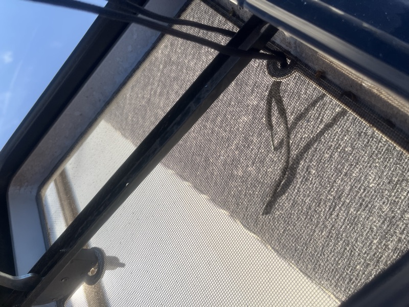 Close-up of the shoelace threaded through a hole in the vent's wire mesh, knotted underneath