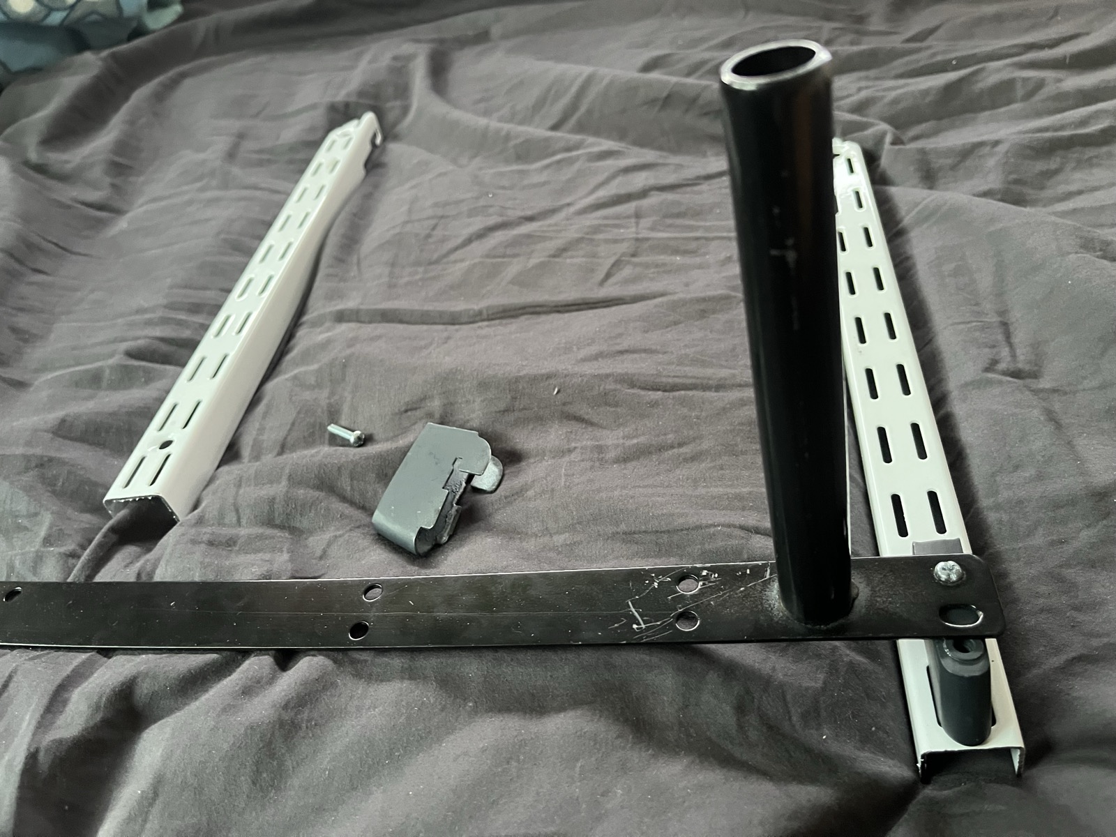Close-up of the wall strip, hook-in bracket, M4 bolt and the shelf mounting bar with its round locating pin